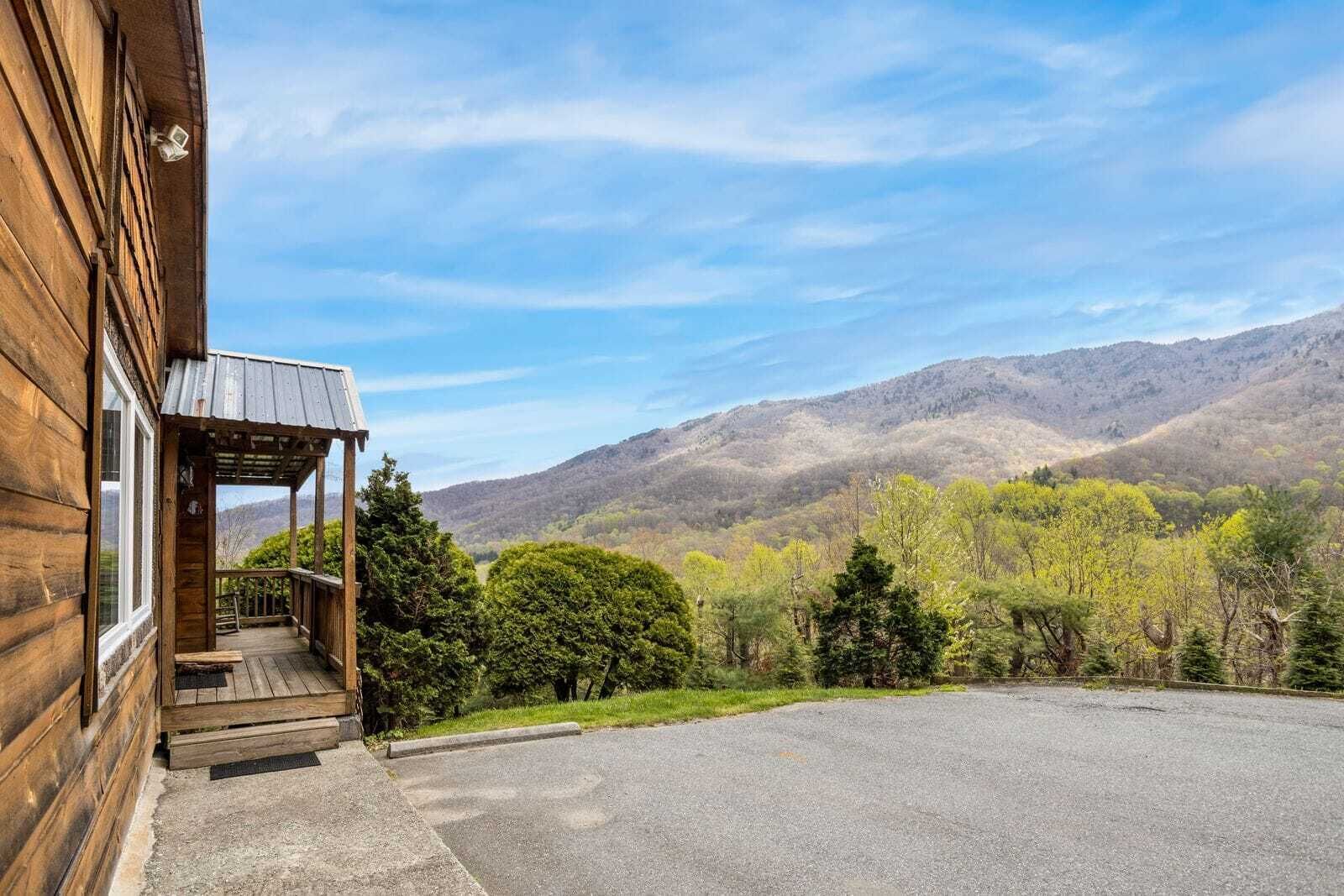 A wooden cabin with a porch and a view of mountains.