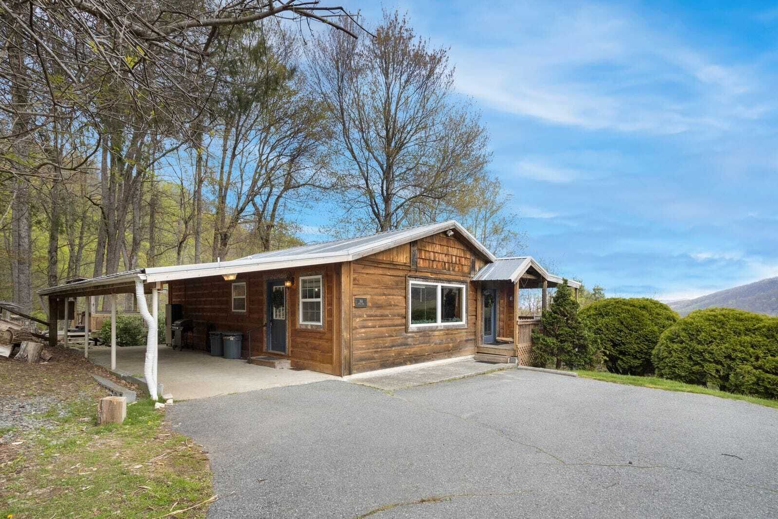A rustic cabin with a covered porch, a front door, and a small attached garage.