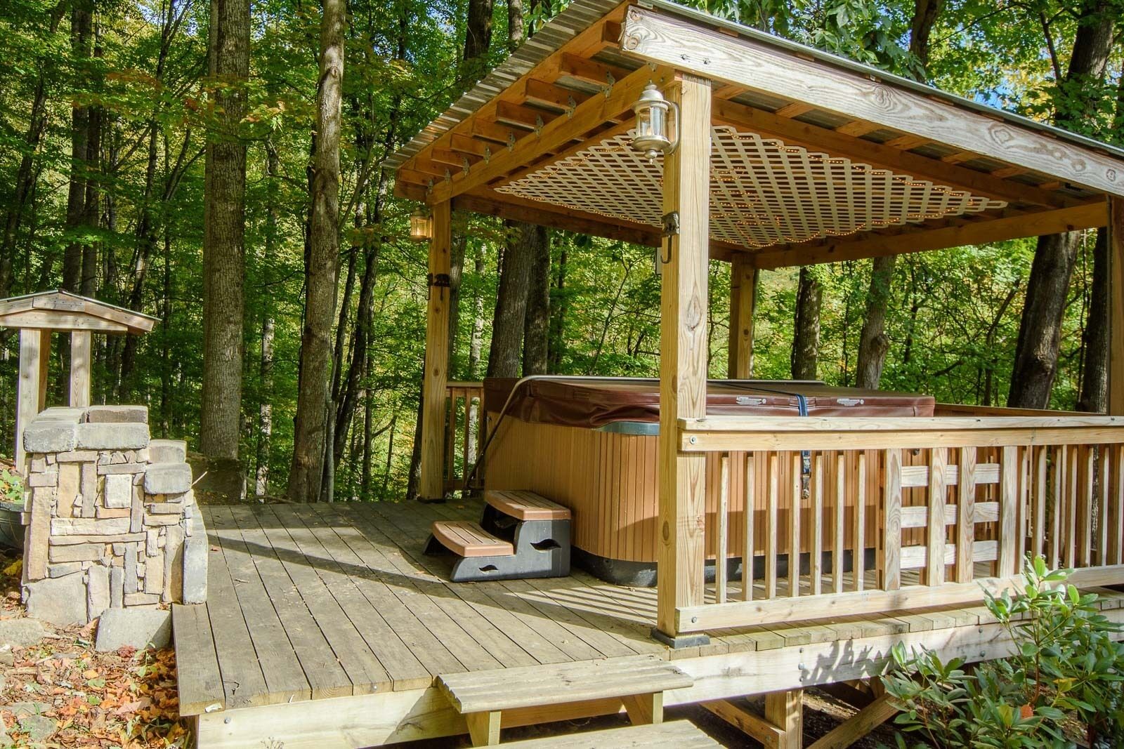 Une terrasse en bois dotée d’un espace salon abrité, d’un escalier en pierre et d’une lanterne.