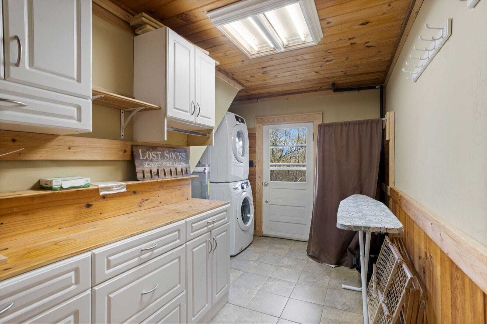 A compact kitchen with wooden cabinets, a washing machine, and a drying rack.