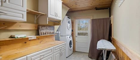 A compact kitchen with wooden cabinets, a washing machine, and a drying rack.