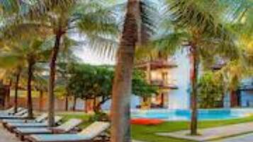 Un resort con palmeras, piscina y sillones de descanso.