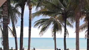 A wooden pathway leading to beachside seating with palm trees. - Duro Beach Hotel (Caucaia)