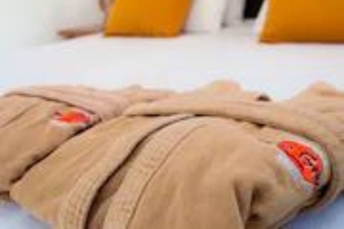 A bed with white and yellow pillows, a black headboard, and a pair of brown pants with a red logo on the side.
