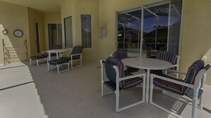 A patio area with white furniture, including a round table and striped chairs, and a ceiling fan. - 1048 TUSC (Davenport)