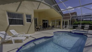 A swimming pool with lounge chairs, a covered patio area, and a view of the surrounding landscape. - 1048 TUSC (Davenport)