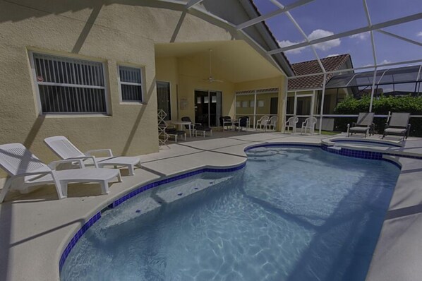 A swimming pool with lounge chairs, a covered patio area, and a view of the surrounding landscape.