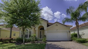 A single-story house with a garage, surrounded by well-maintained landscaping and trees. - 1048 TUSC (Davenport)