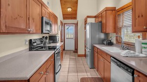 A kitchen with wooden cabinets, a stove, a microwave, and a refrigerator. - 2 Master Suite Cabin! Walk to Appalachian Ski Mtn. Hot Tub, Game Room & Fire Pit (Blowing Rock)