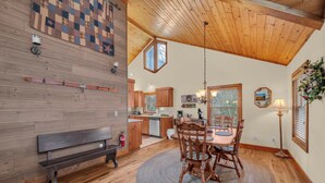 A cozy kitchen with wooden cabinets, a dining table with chairs, and a bench. - 2 Master Suite Cabin! Walk to Appalachian Ski Mtn. Hot Tub, Game Room & Fire Pit (Blowing Rock)