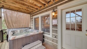 A wooden deck with a hot tub, a door with a window, and a wall-mounted light fixture. - 2 Master Suite Cabin! Walk to Appalachian Ski Mtn. Hot Tub, Game Room & Fire Pit (Blowing Rock)