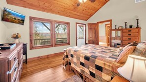 A bedroom with a wooden ceiling, a bed with a quilt, a dresser, a desk, and a window with blinds. - 2 Master Suite Cabin! Walk to Appalachian Ski Mtn. Hot Tub, Game Room & Fire Pit (Blowing Rock)