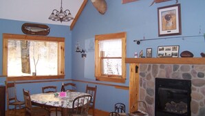 A dining area with a stone fireplace, wooden dining table, and chairs.