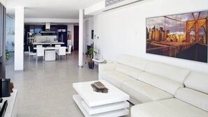 A modern living room with a white sofa, a coffee table, and a cityscape painting on the wall. - Casa Pane (Ibiza Town)