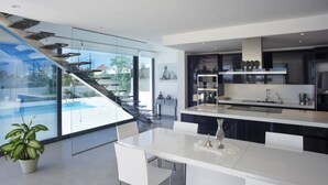 A modern kitchen with a central island, a glass staircase, and a view of a swimming pool. - Casa Pane (Ibiza Town)