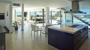 A modern kitchen with a central island, large windows, and a view of the outdoors. - Casa Pane (Ibiza Town)