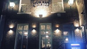 A building with a sign reading "LIL'S BAR BISTRO" and multiple illuminated windows. - Lil's Bar and Bistro (York)