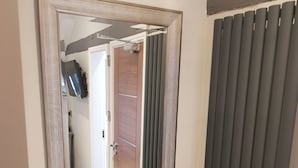 A mirror with a metal frame, a radiator, and a door with a wooden panel. - Lil's Bar and Bistro (York)
