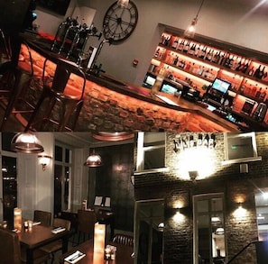 Een bar met een stenen muur, een klok en een wijnrek.