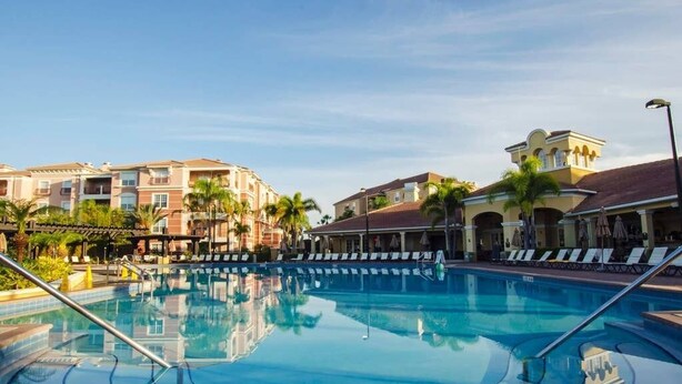 A swimming pool with lounge chairs and palm trees, surrounded by multi-story buildings with balconies. - *BRAND NEW! * CHARMING ORLANDO VISTA CAY  3/BR  2/ FULL BATH CONDO  *SLEEPS 6-8* (Orlando)