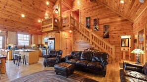 A spacious log cabin interior with a kitchen, dining area, and a staircase leading to an upper level. - Perfect Mountain Getaway with Amazing Views (Banner Elk)