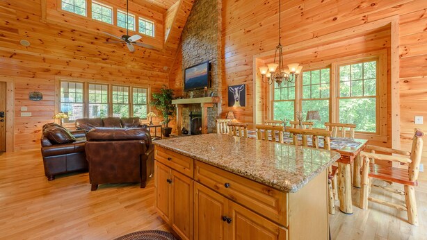 A log cabin interior with a fireplace, wooden furniture, and large windows. - Perfect Mountain Getaway with Amazing Views (Banner Elk)