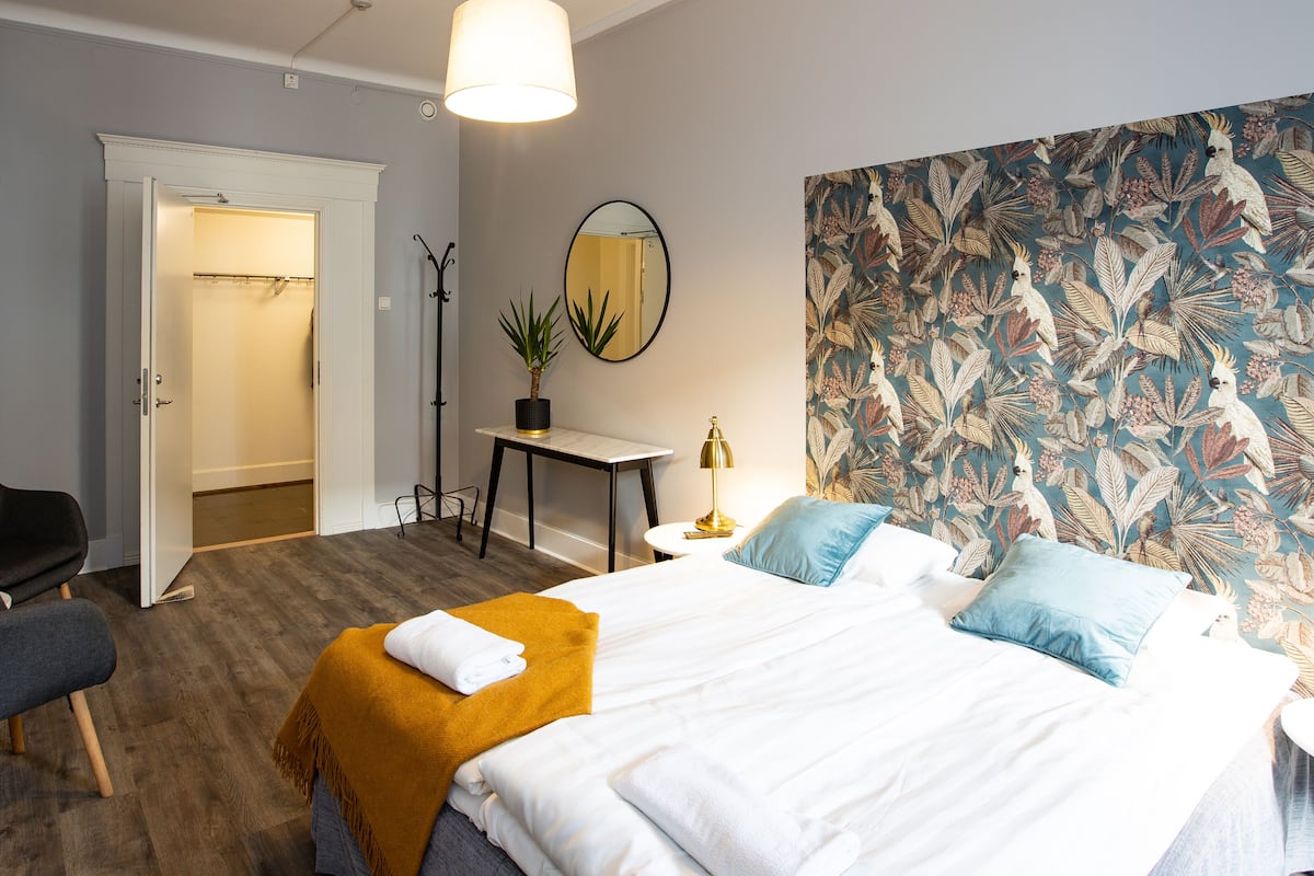 A hotel room with a bed, a desk, a chair, and a mirror.