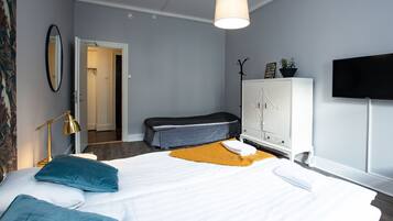 A modern hotel room with a large bed, a bedside lamp, a television, and a wardrobe.