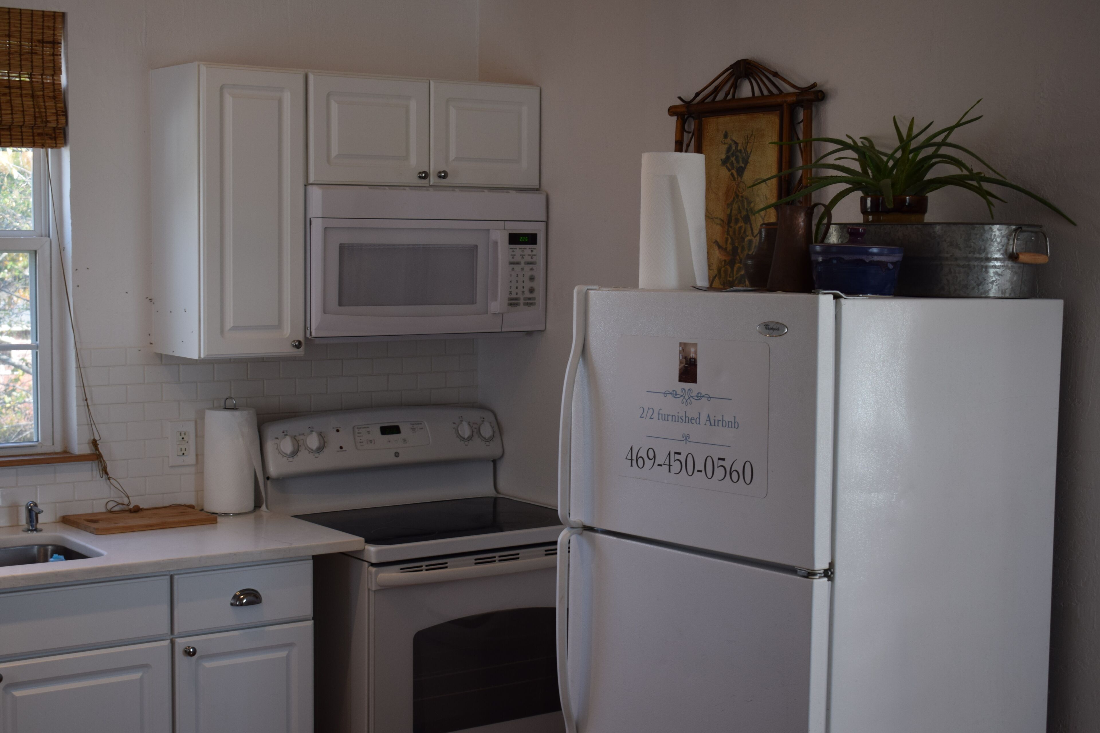 A kitchen with white cabinets, a microwave, a stove, and a refrigerator.