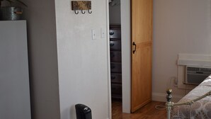 Een kamer met een houten kast, een radiator en een bed met beddengoed met een patroon.