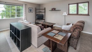 Una sala de estar con un sofá, una mesa de centro, un televisor y una estantería.