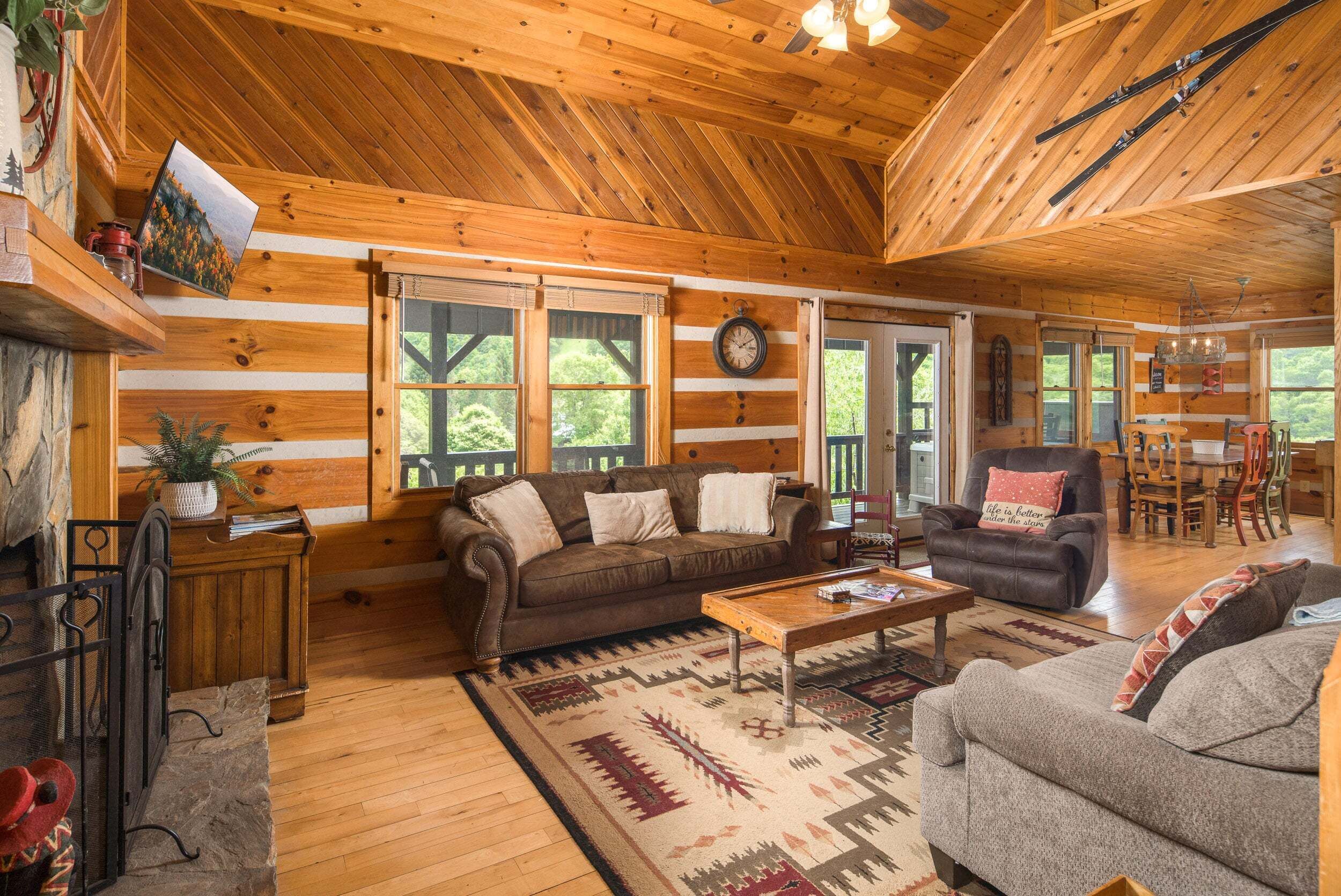 A wooden cabin interior with a sofa, coffee table, and dining area.