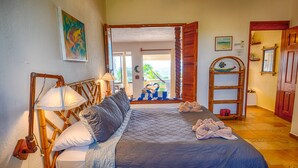 Een slaapkamer met een bed, een lamp, een schilderij en uitzicht op het omliggende landschap.