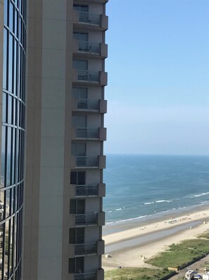 A high-rise building with balconies overlooking a beach and ocean.