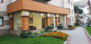 Um edifício moderno com grandes janelas, um jardim bem cuidado e um caminho pavimentado.
