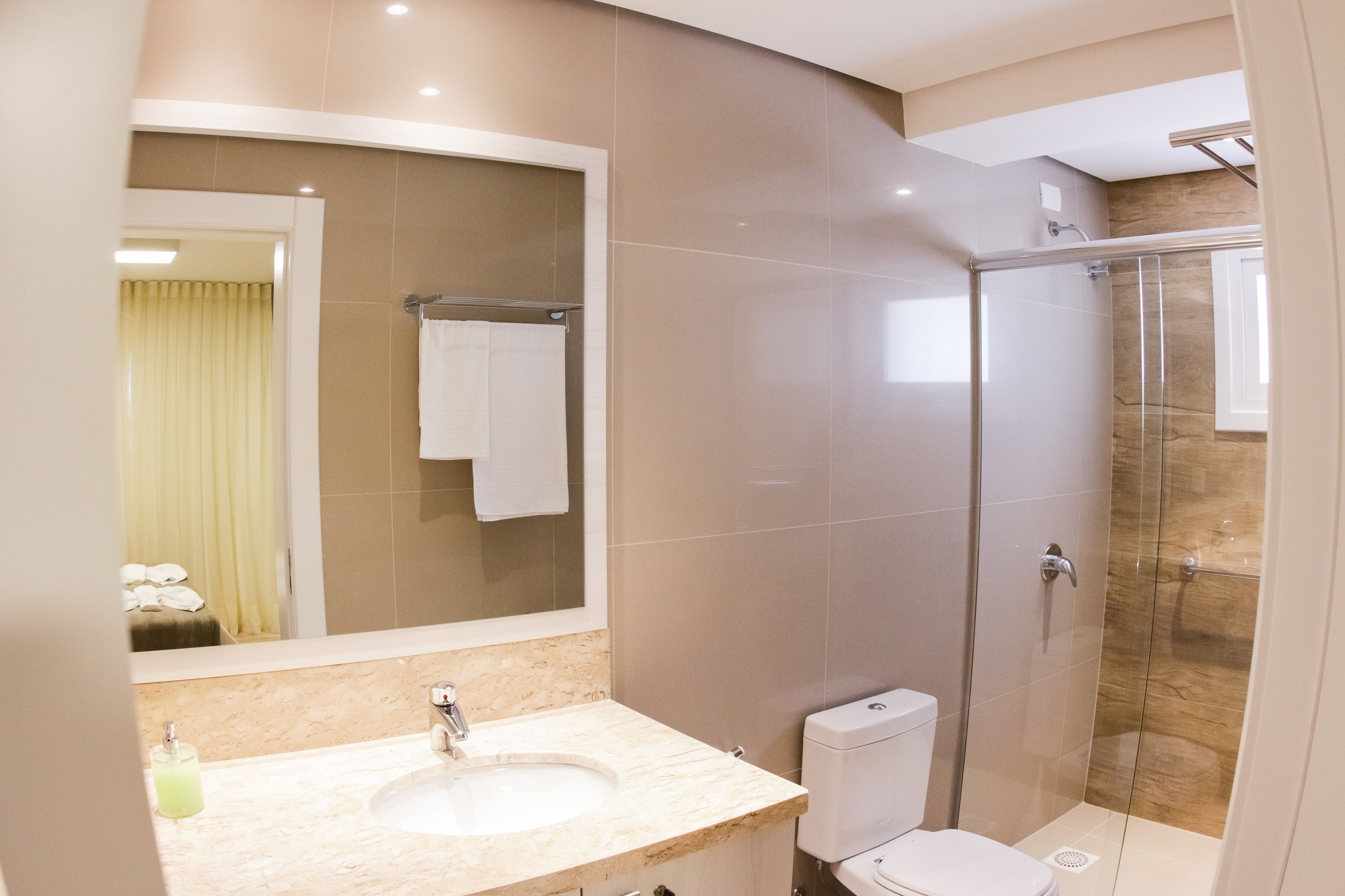 Une salle de bain moderne avec un grand miroir, un lavabo, des toilettes et une douche à parois de verre.