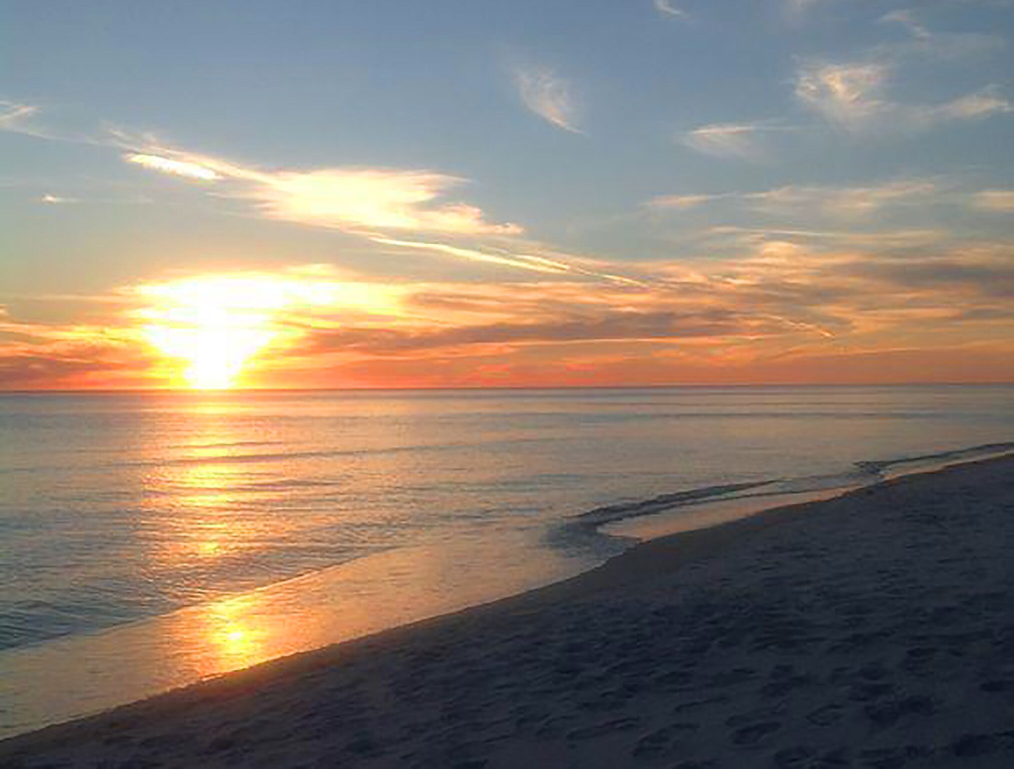Una playa con un atardecer sobre el océano.