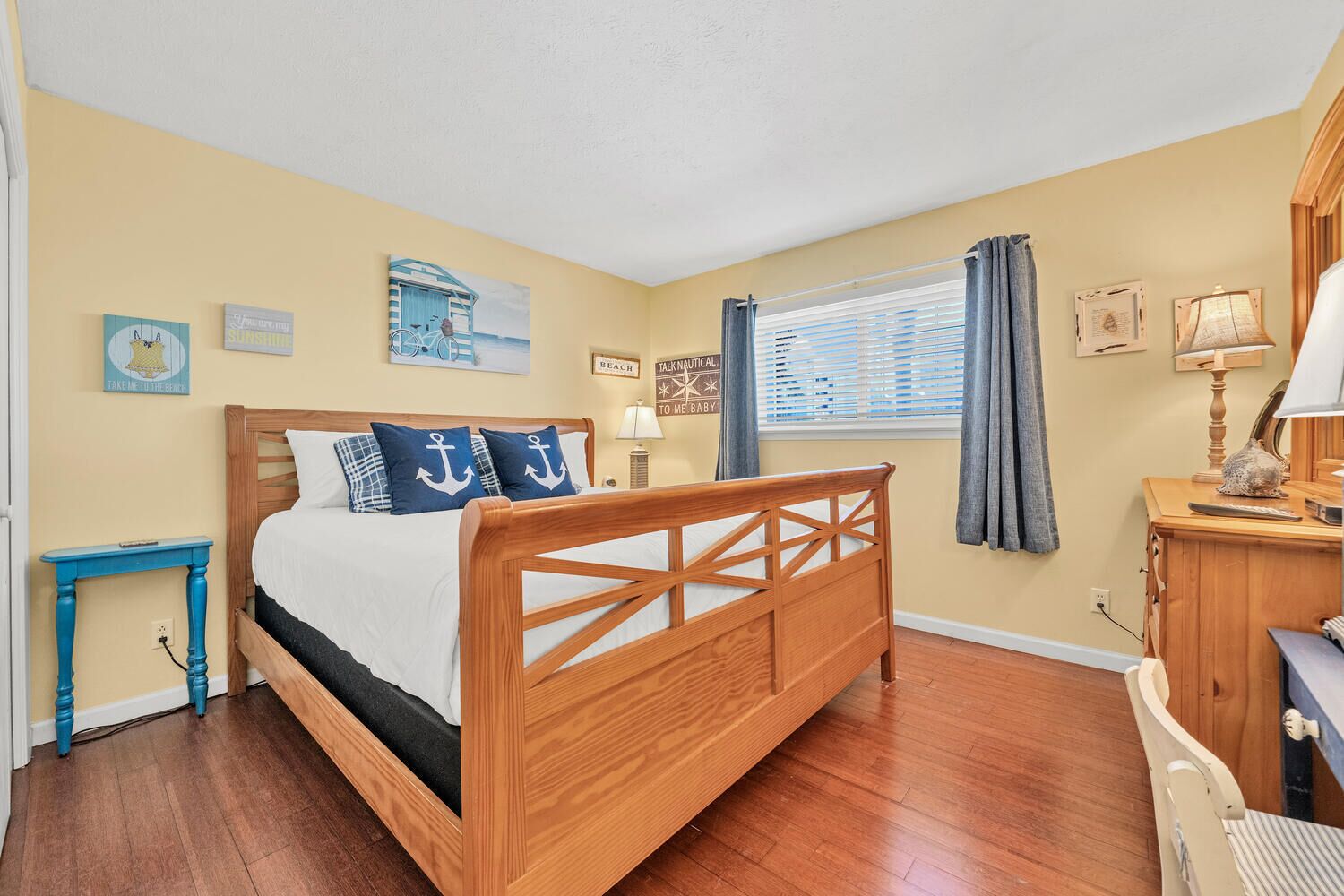 Une chambre à coucher avec un lit en bois, une petite table de chevet, un bureau avec une lampe et des décorations murales sur le thème de la marine.