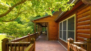 Une cabane en bois dotée d’un porche abrité et de grandes fenêtres.
