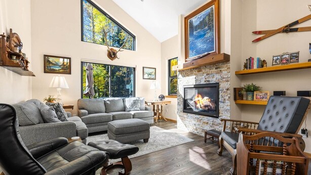 A modern living room with a fireplace, leather sofas, and a television. - Mountainside 523 3 Bedroom Home by RedAwning (Frisco)