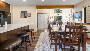 A modern kitchen with a bar area, wooden cabinets, and a dining table with chairs. - Mountainside 523 3 Bedroom Home by RedAwning (Frisco)