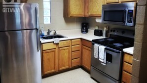 A kitchen with wooden cabinets, a stainless steel refrigerator, a microwave, and an oven. - The 87Getaway Cabin #1 (Mountain View)