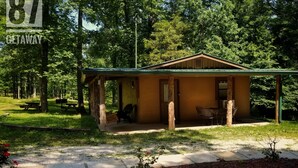 A small, single-story building with a porch, surrounded by trees. - The 87Getaway Cabin #1 (Mountain View)