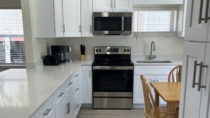 Une cuisine moderne avec des meubles blancs, des appareils en acier inoxydable et une table à manger en bois.