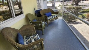 Un espace extérieur abrité, aménagé avec des meubles en osier et doté d’un ventilateur de plafond.