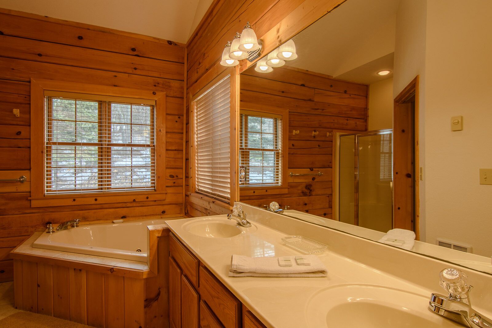 Une salle de bain rustique, avec deux lavabos, une baignoire et un grand miroir.