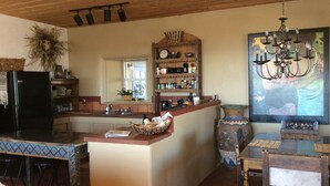 Una cocina con una isla central, armarios de madera, un refrigerador y una araña.