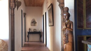 Un pasillo con una estatua de madera, una cruz y cuadros en las paredes.
