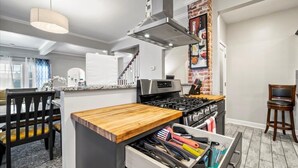 Una cocina moderna con encimera de madera, electrodomésticos de acero inoxidable y una pared decorativa de ladrillo.