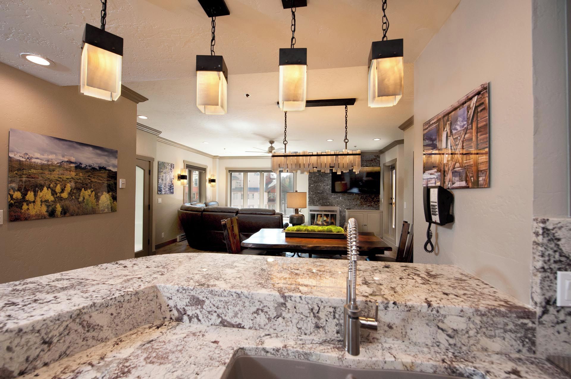 A kitchen with granite countertops, a built-in stove, and hanging pendant lights.